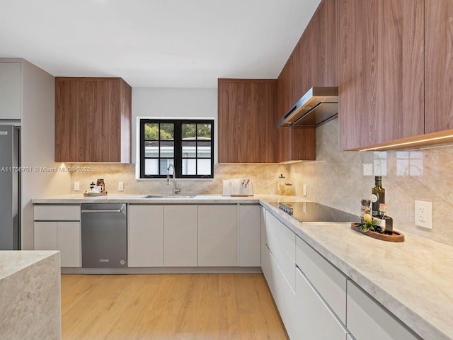 kitchen featuring range hood, modern cabinets, a sink, and black electric cooktop