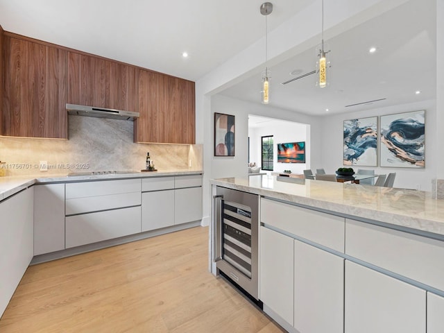 kitchen featuring black electric cooktop, ventilation hood, light stone countertops, backsplash, and beverage cooler