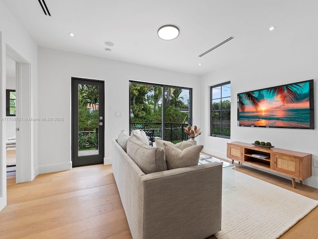 living area with baseboards, recessed lighting, light wood-style floors, and a healthy amount of sunlight