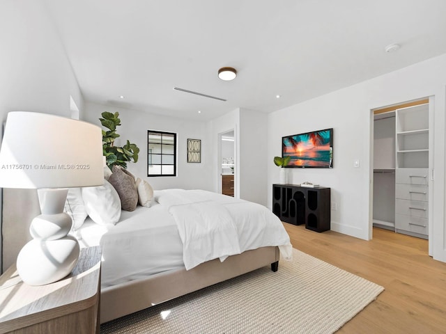 bedroom with light wood finished floors, baseboards, and a spacious closet