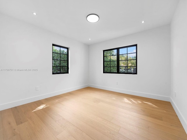 empty room with baseboards, light wood finished floors, and recessed lighting