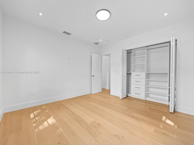 unfurnished bedroom featuring light wood-style flooring, visible vents, baseboards, and a closet