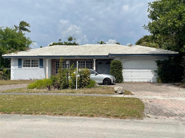 single story home with a tiled roof, decorative driveway, an attached garage, and stucco siding