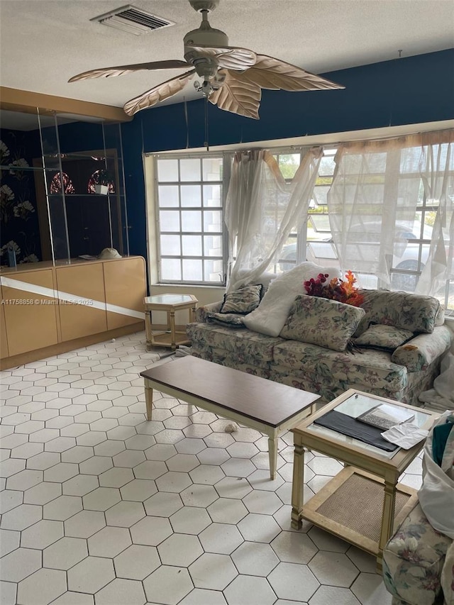 unfurnished living room featuring a ceiling fan, visible vents, and a textured ceiling