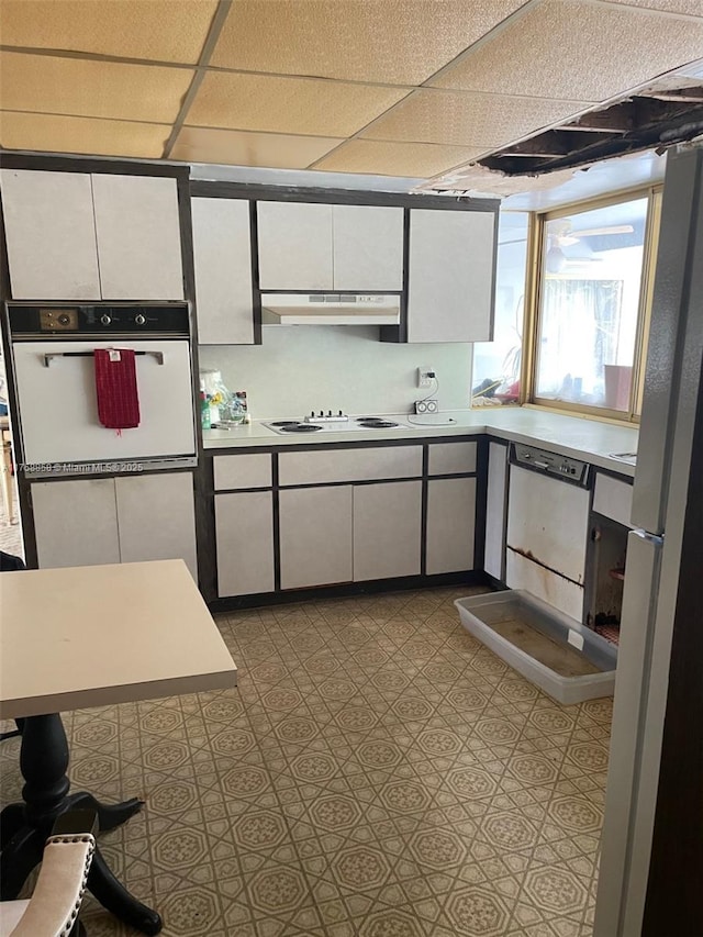 kitchen with under cabinet range hood, white appliances, white cabinets, and light countertops