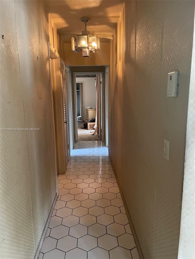 hallway featuring a notable chandelier and light tile patterned flooring