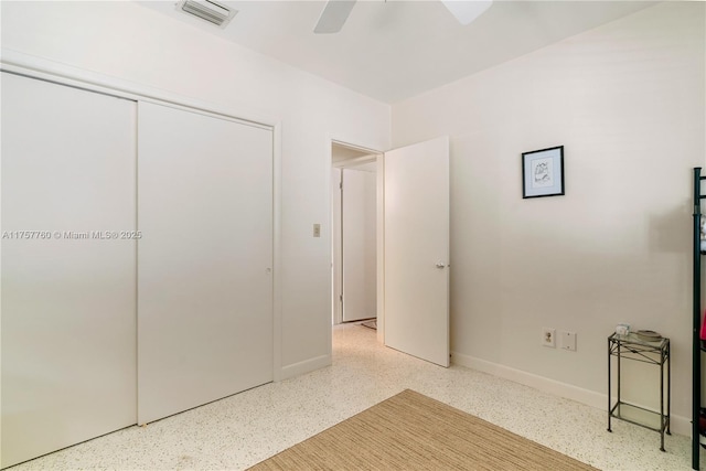 unfurnished bedroom with a closet, visible vents, ceiling fan, baseboards, and speckled floor