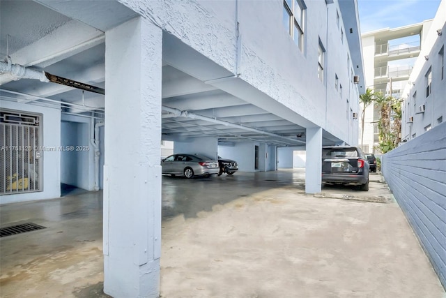 view of car parking featuring a parking garage and visible vents