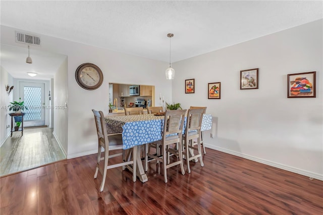 dining space featuring baseboards, visible vents, and wood finished floors