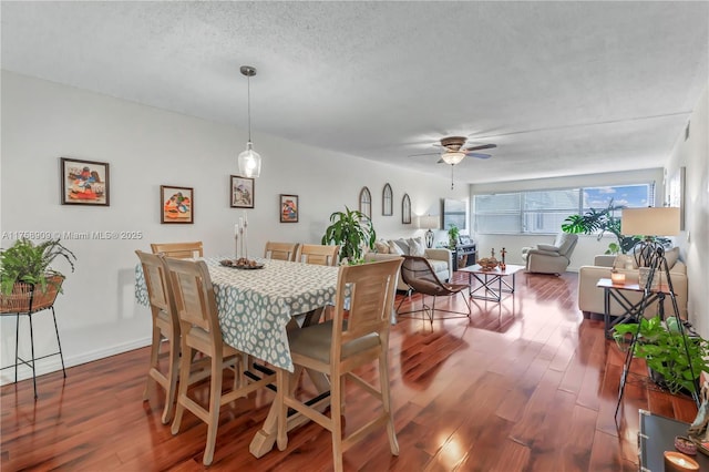 dining area featuring dark wood-style floors, ceiling fan, a textured ceiling, and baseboards