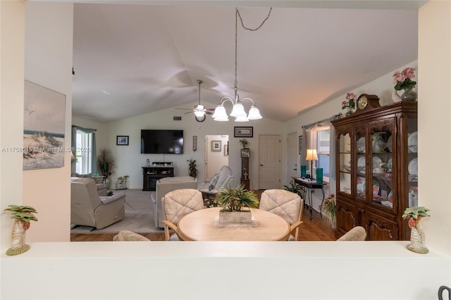 dining space featuring vaulted ceiling, wood finished floors, and an inviting chandelier