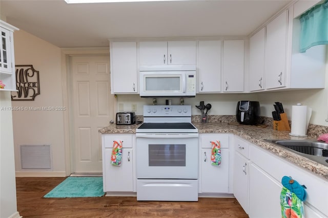 kitchen featuring white appliances, wood finished floors, visible vents, and white cabinets