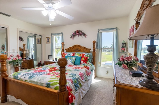 bedroom featuring light carpet, ceiling fan, multiple windows, and visible vents