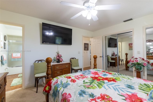 bedroom with two closets, light colored carpet, visible vents, a ceiling fan, and connected bathroom