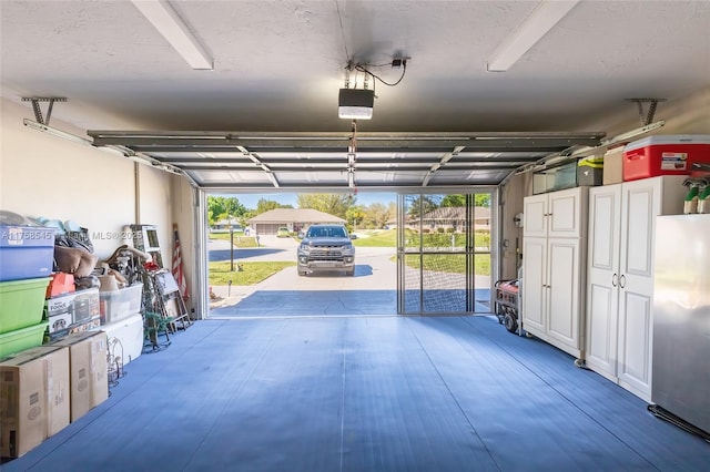 garage featuring a garage door opener and freestanding refrigerator