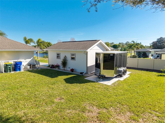 back of property featuring a shingled roof, a lawn, fence, and stucco siding