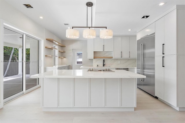 kitchen featuring decorative backsplash, appliances with stainless steel finishes, white cabinetry, a kitchen island, and a sink