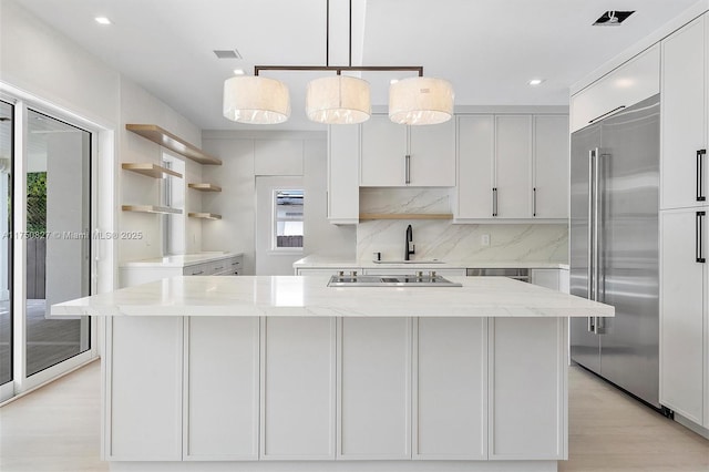 kitchen with built in fridge, a center island, light stone counters, open shelves, and tasteful backsplash