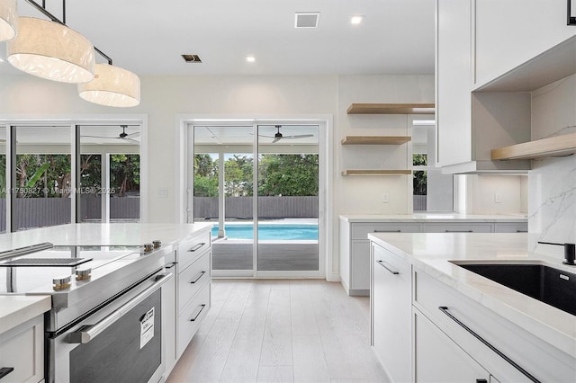 kitchen with decorative backsplash, electric stove, light stone counters, white cabinetry, and open shelves