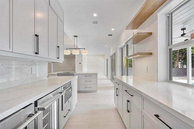 kitchen featuring light stone counters, pendant lighting, visible vents, and open shelves