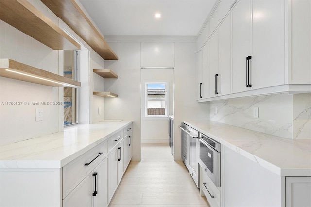 kitchen featuring light stone counters, white cabinetry, decorative backsplash, and open shelves