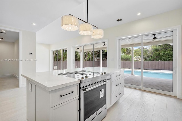 kitchen with hanging light fixtures, stainless steel electric range, light stone countertops, and white cabinets