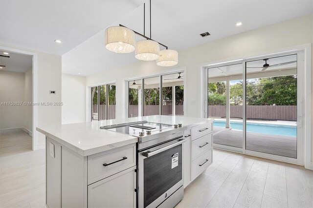 kitchen with hanging light fixtures, stainless steel electric range, light stone countertops, and white cabinets