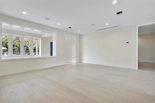 empty room with light wood-style floors, recessed lighting, visible vents, and baseboards