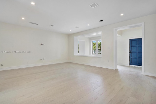 unfurnished room featuring light wood-style floors, visible vents, and baseboards