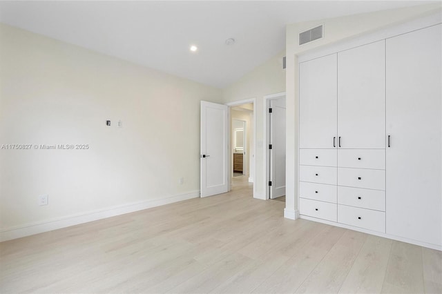 unfurnished bedroom with lofted ceiling, a closet, visible vents, light wood-style floors, and baseboards