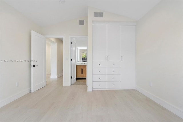 unfurnished bedroom featuring light wood-style flooring, visible vents, vaulted ceiling, and baseboards