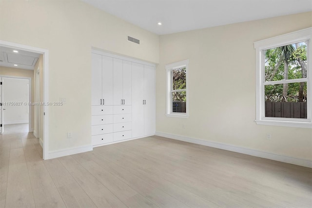 unfurnished bedroom with light wood finished floors, lofted ceiling, recessed lighting, visible vents, and baseboards