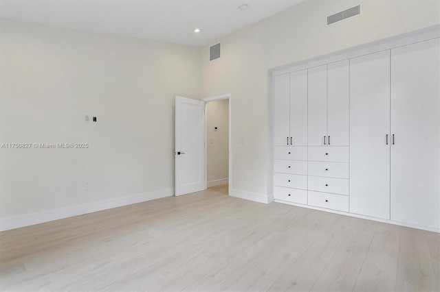 unfurnished bedroom with light wood-type flooring, baseboards, visible vents, and a closet