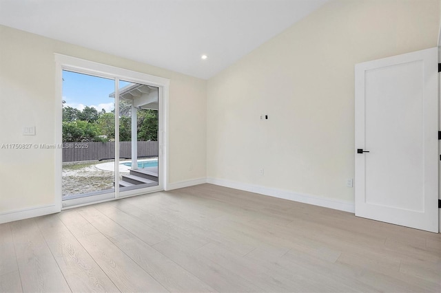 spare room featuring lofted ceiling, recessed lighting, baseboards, and wood finished floors