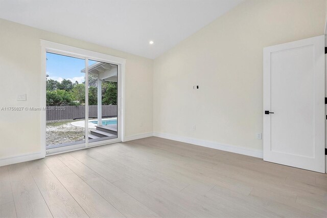 spare room featuring lofted ceiling, recessed lighting, baseboards, and wood finished floors