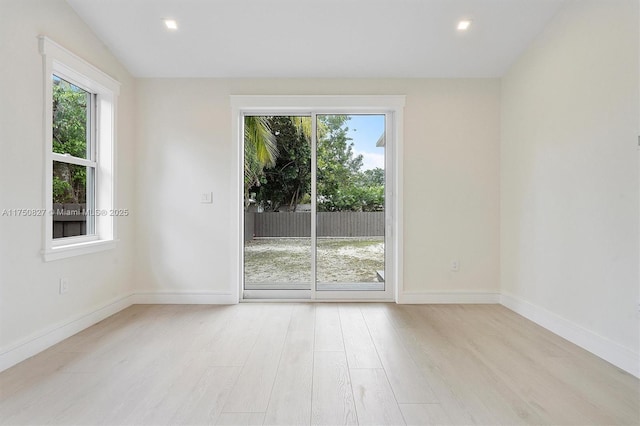 unfurnished room featuring baseboards, a wealth of natural light, and wood finished floors