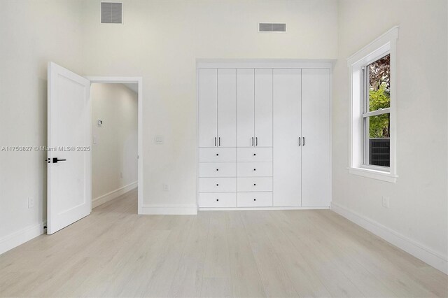 unfurnished bedroom featuring visible vents, light wood-style flooring, and baseboards
