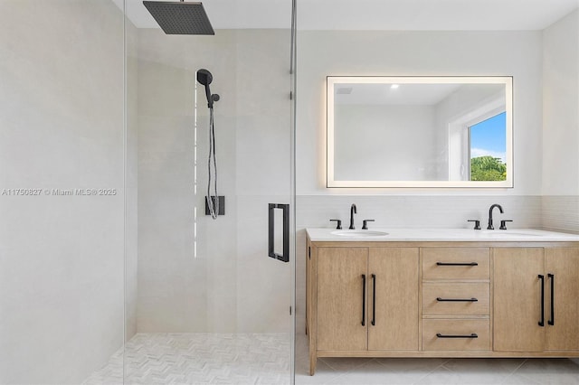 full bath featuring double vanity, a stall shower, and a sink