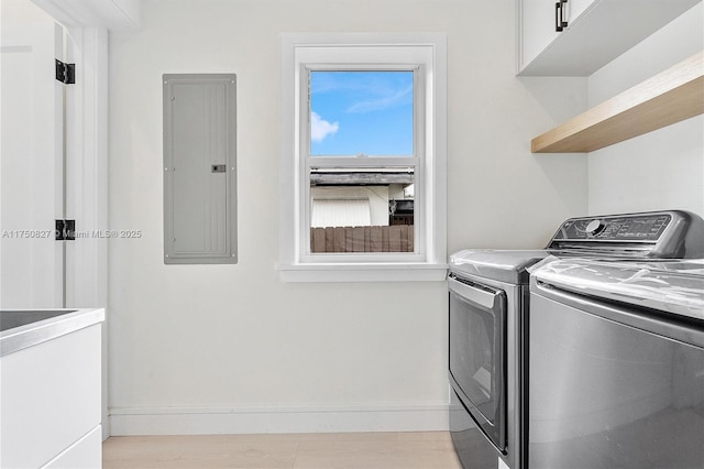 laundry area featuring washing machine and clothes dryer, cabinet space, light wood-style flooring, electric panel, and baseboards