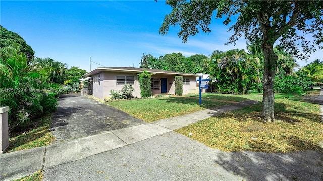 view of front facade featuring driveway, stucco siding, and a front yard