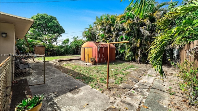 view of yard featuring a patio area, a fenced backyard, a storage unit, and an outdoor structure