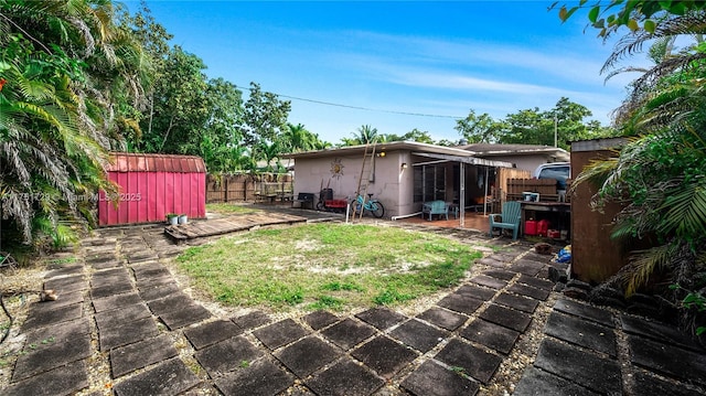 view of yard with a patio, a storage unit, an outdoor structure, and fence