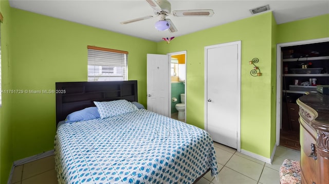 bedroom with visible vents, light tile patterned flooring, connected bathroom, ceiling fan, and baseboards