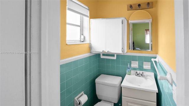 bathroom featuring toilet, plenty of natural light, vanity, and wainscoting