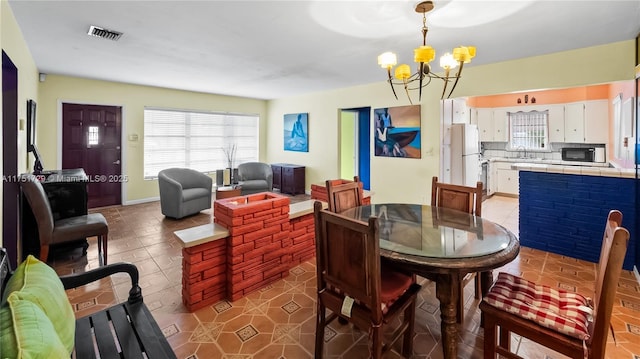 dining room with tile patterned flooring, visible vents, and an inviting chandelier