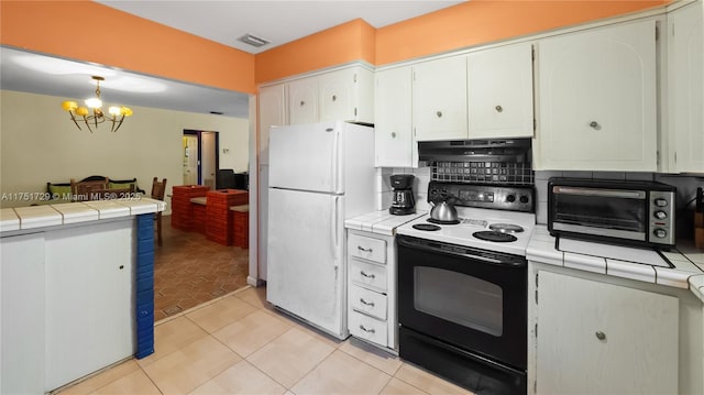 kitchen featuring tile countertops, a toaster, under cabinet range hood, electric range, and freestanding refrigerator