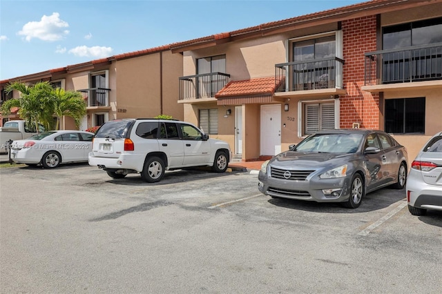 exterior space featuring uncovered parking, a tiled roof, and stucco siding