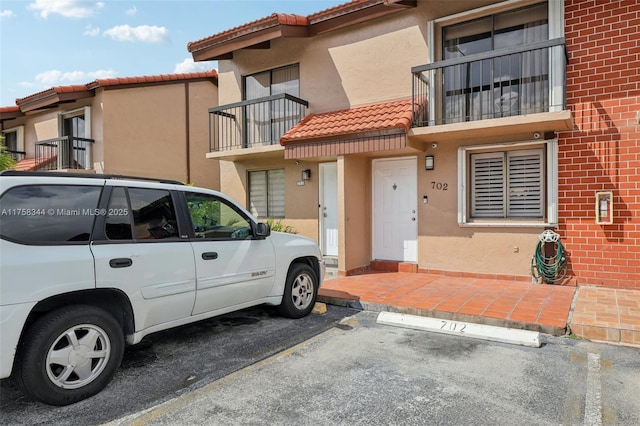 exterior space with a tile roof, uncovered parking, and stucco siding