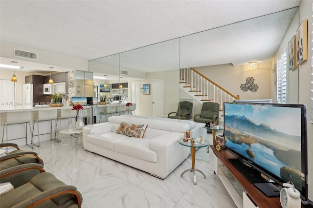 living area with stairway, marble finish floor, visible vents, and a textured ceiling