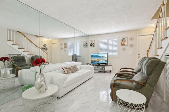 living area featuring marble finish floor, stairway, and a textured ceiling